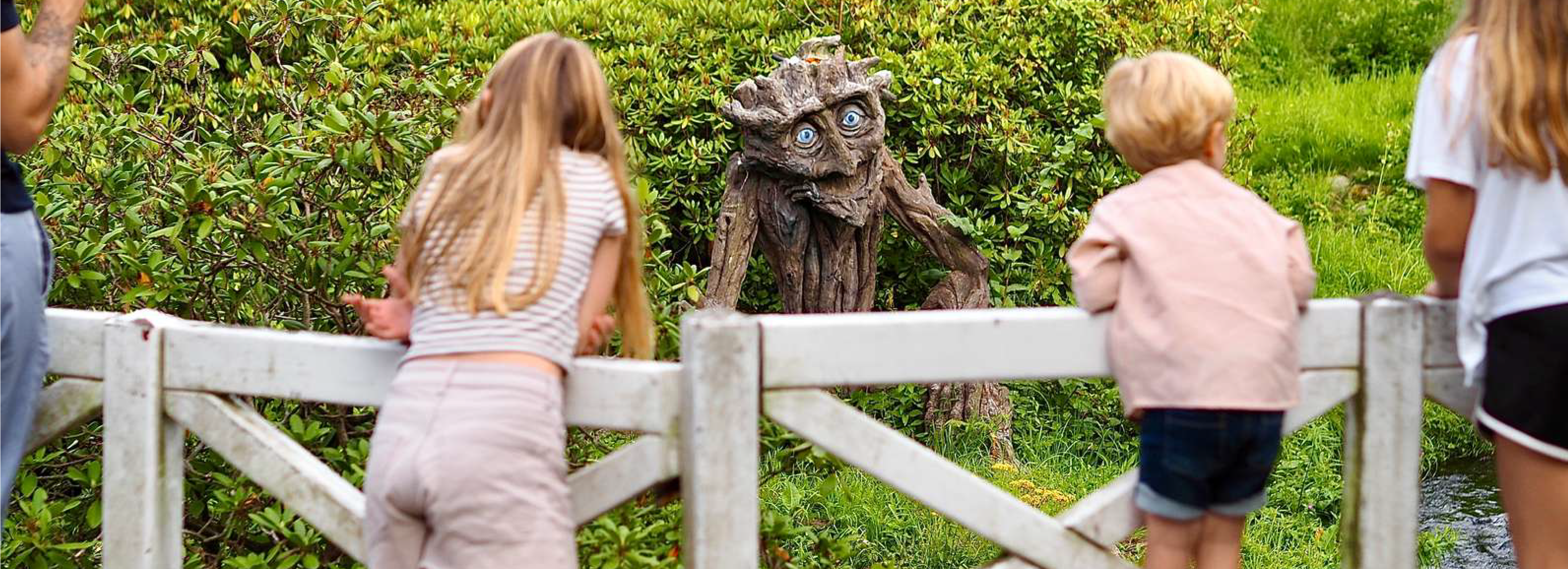 Børn kigger på en trold af træ udendørs