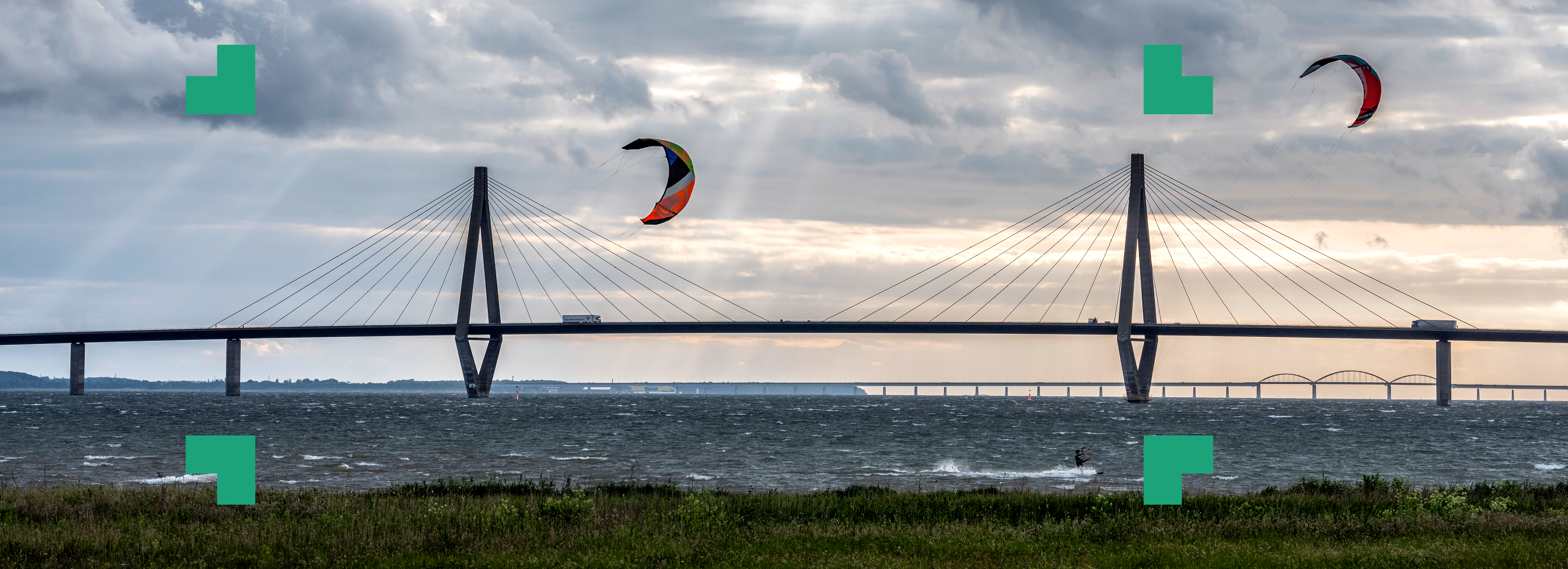 Billede af windsurfersejl der flyver ved bro